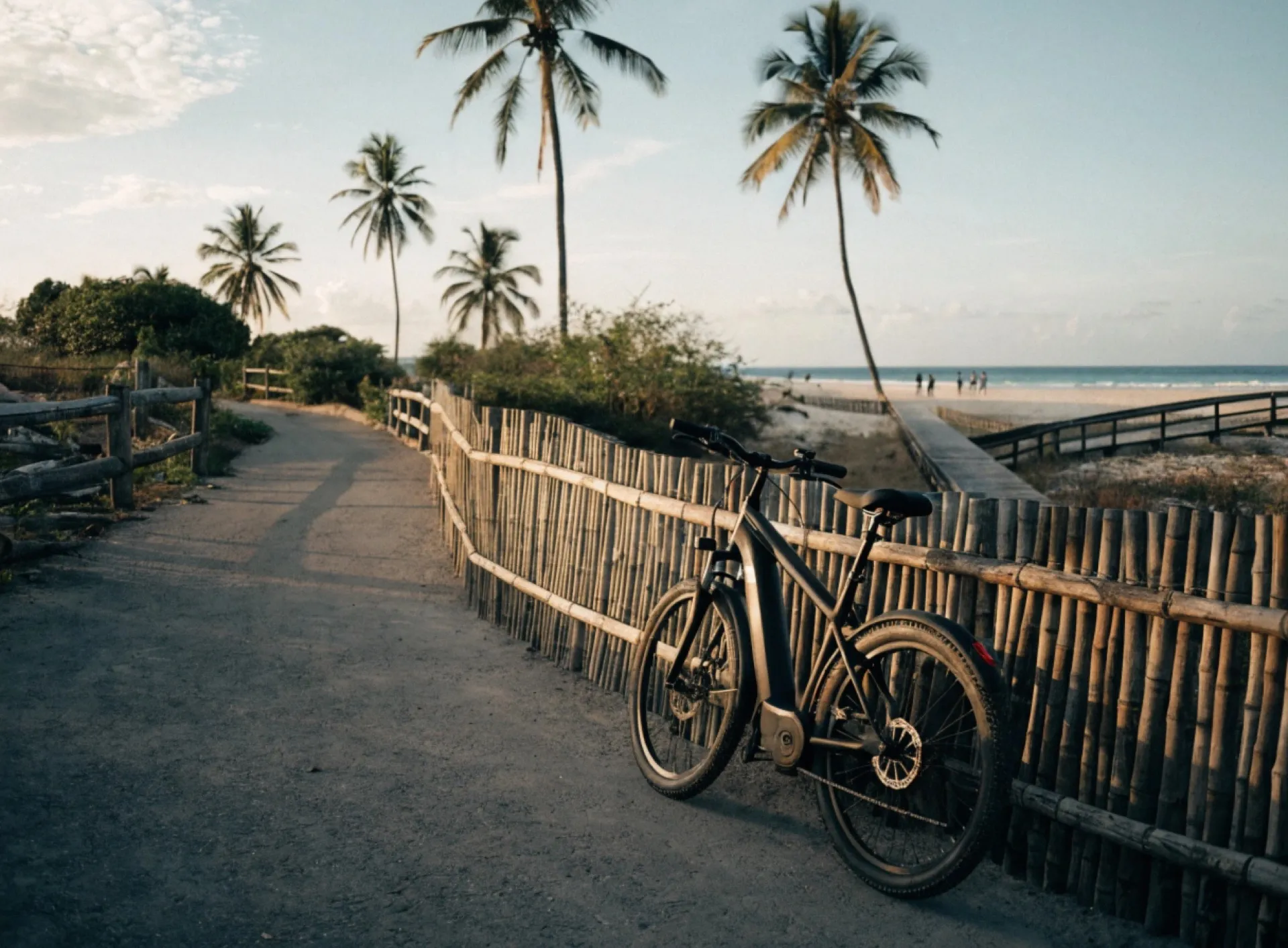 Modern step-through electric bike with integrated battery, parked along a bamboo fence on a sandy coastal path near Cloud 9 on Siargao Island