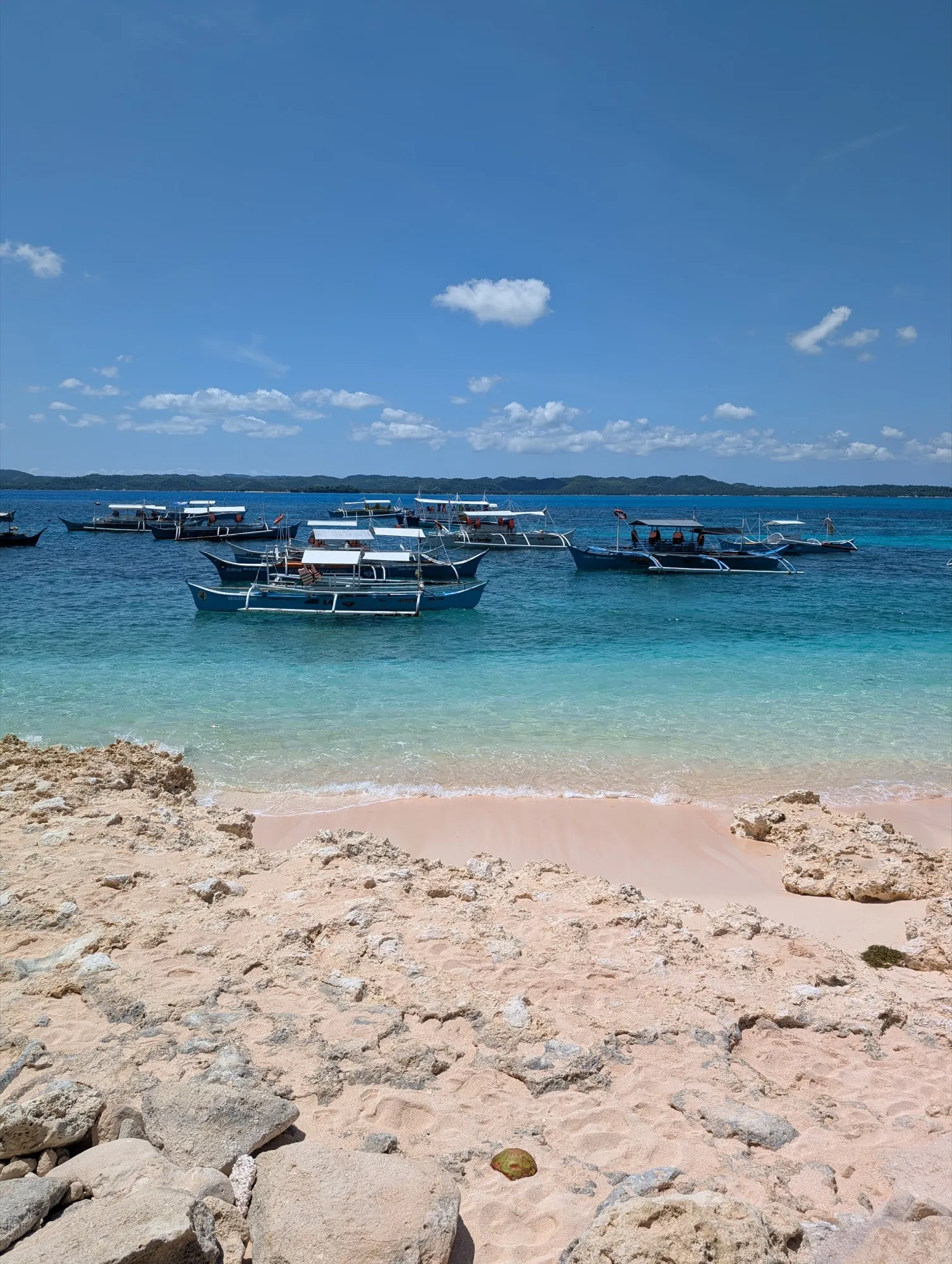 Traditional Filipino bangka boats on turquoise water and pink sand beach near General Luna, Siargao — the kind of stop you can chain after the easy loop